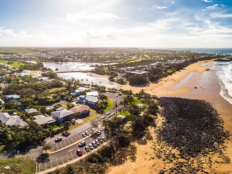 Aerial view of Bargara beach with sun in distance showing an incredible lifestyle available